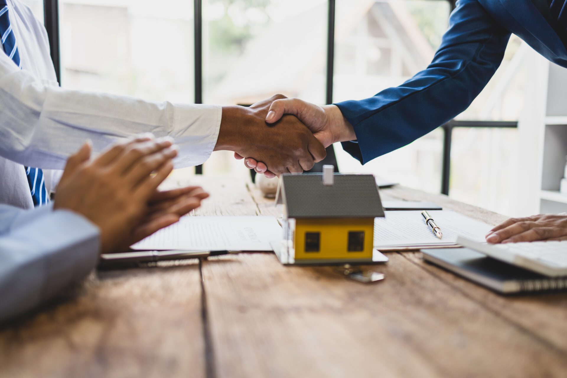 Handshake over table with house model.