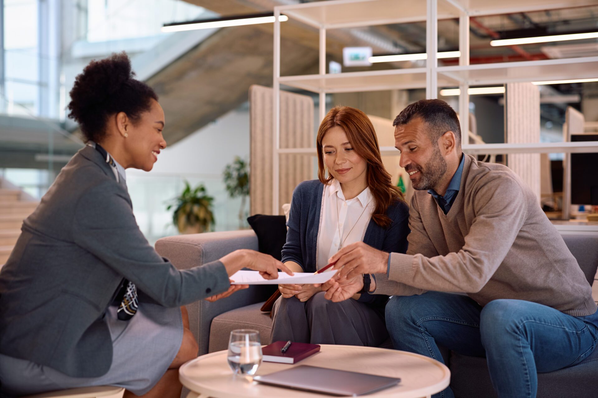 Business meeting with three people discussing documents.